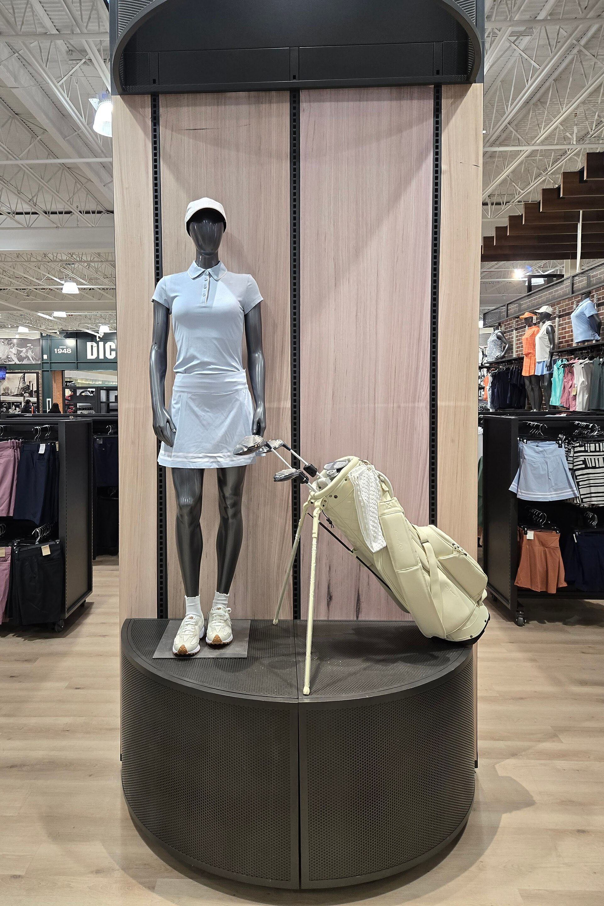 A mannequin wearing Calia branded golf apparel with some golf clubs next to it. Calia is a name brand of Dick's that sells activewear and ap