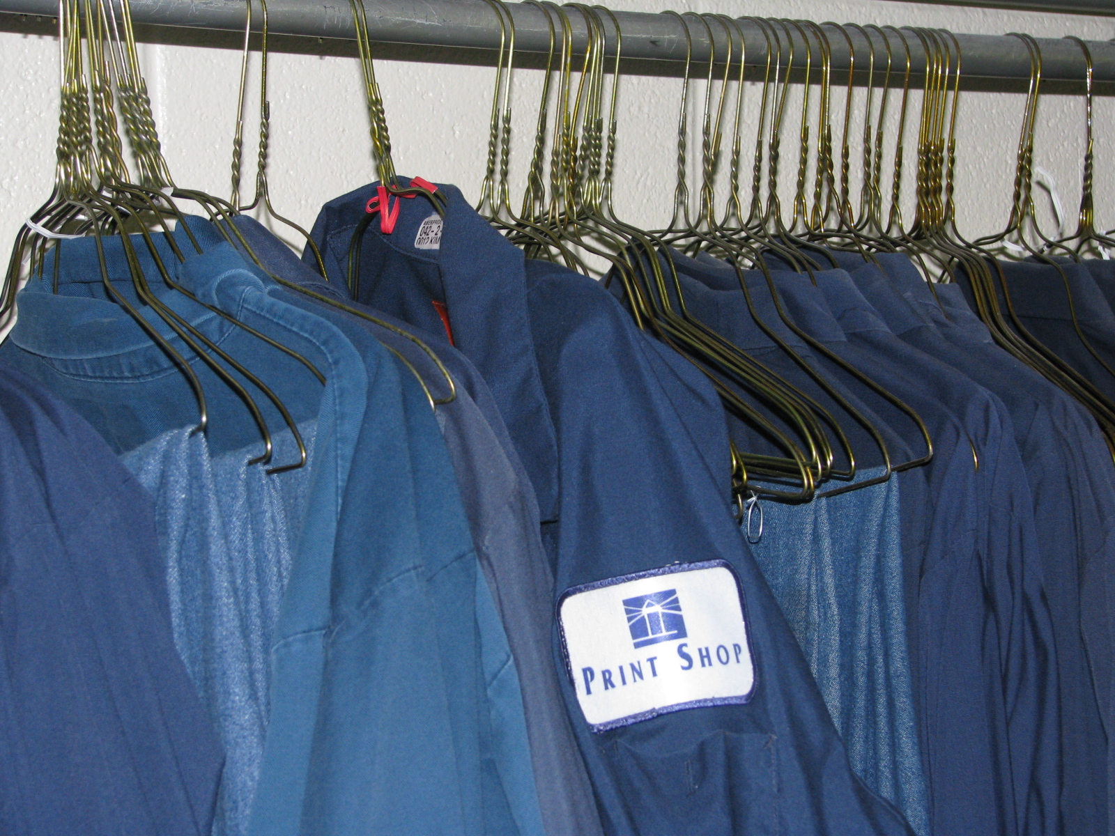 Work uniforms in a clothes rack in the CA print shop.