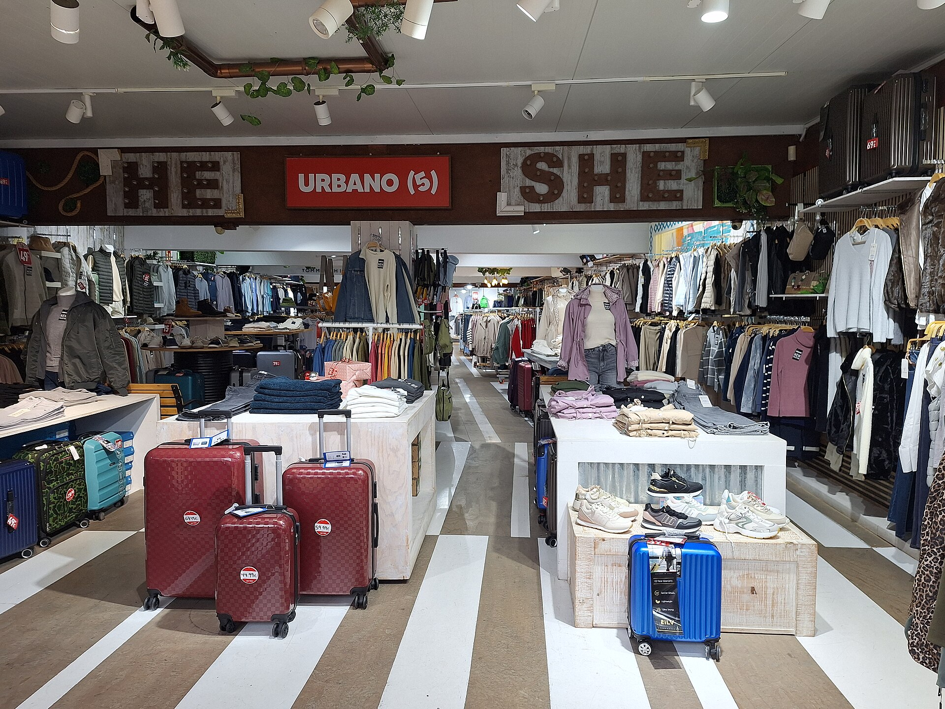 Interior view of a clothing store in the pedestrian zone of Son Moro, Cala Millor (Mallorca). The elongated sales area shows clothing racks