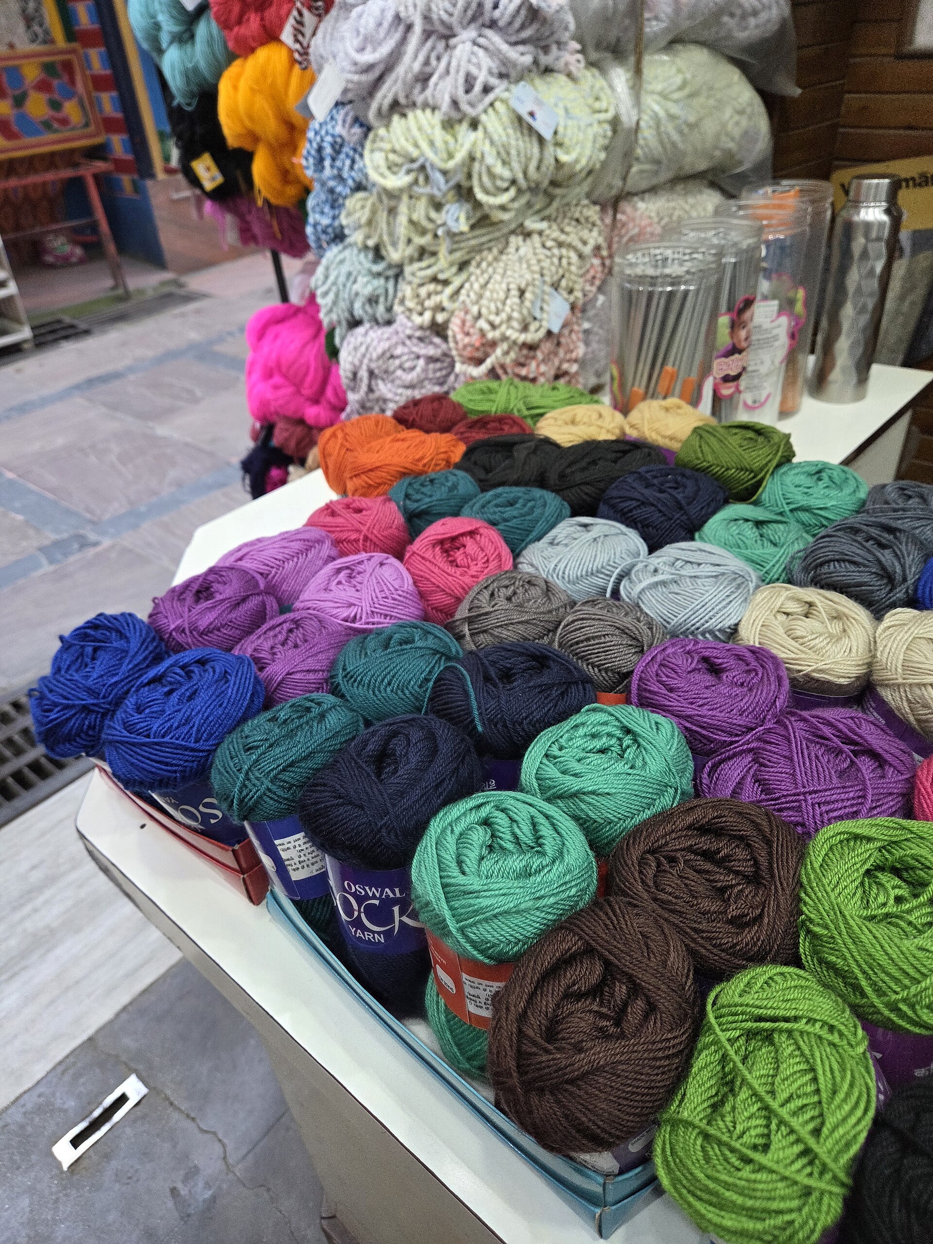 A variety of colorful yarn skeins displayed in a shop, used for knitting, crocheting, and other textile crafts.