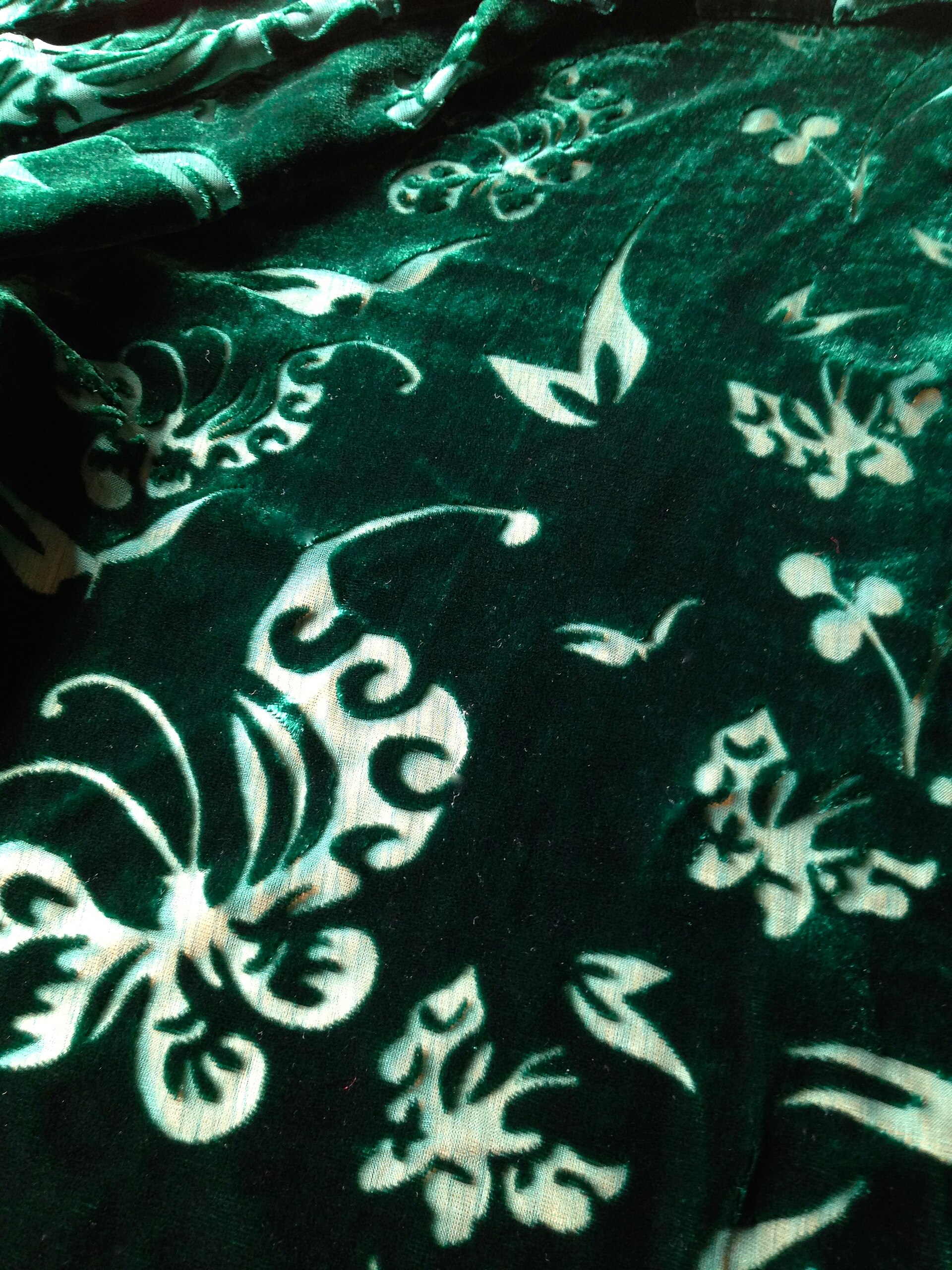 Green devoré velvet fabric. Devoré (or burnout) is a technique particularly used on velvets. Chemical is applied to fabric in order to disso